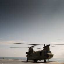 Chinook helicopter on flight deck of RAN LHD with flying Chinook in background