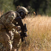 Soldier crouched in dry waist high grass