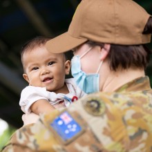 Australian Army officer Captain Sarah Kelly, Public Affairs Officer deployed on Pacific Partnership 2022, holds a child from the local community at Macarascas Elementary School, Palawan, Philippines.