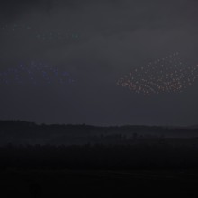 Drones flying above an enemy position demonstrate in concept surveillance (green), electronic warfare (blue), and attack (orange) capabilities during a human-machine team exercise at Puckapunyal Military Area.