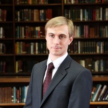 Profile picture of Dr Jack Watling with library in the background.