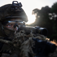 Australian soldier looking down his weapon, with full gear on.