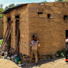 A small housing structure in Mozambique Africa with a young child in the foreground; cover of Irregular Warfare Essay collection at bottom right