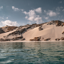 Hilly sandy shoreline viewed from water level away from shore